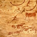Pintura rupestre com figuras humanas e animais em representação de uma cena de caça
