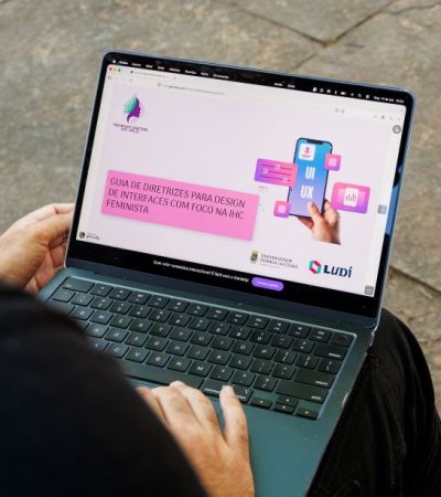 Pessoa utiliza notebook que exibe o Guia de Diretrizes para Design de Interfaces com Foco em IHC Feminista.