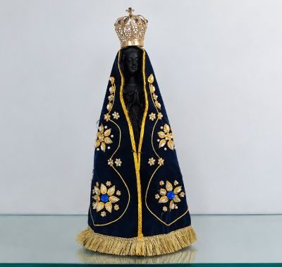 Imagem de Nossa Senhora Aparecida com manto azul-marinho bordado em dourado e coroa ornamentada.