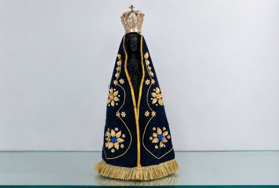 Imagem de Nossa Senhora Aparecida com manto azul-marinho bordado em dourado e coroa ornamentada.