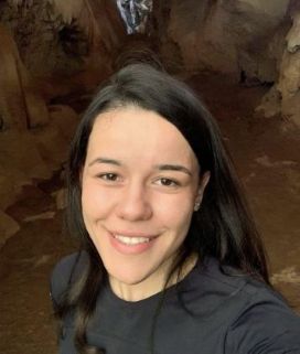 Pesquisadora Thais Oliveira sorrindo para a câmera durante visita a uma caverna na Bahia.