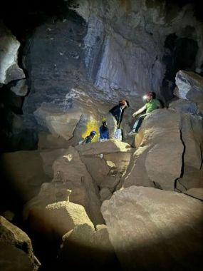 Grupo de visitantes explorando o interior de uma caverna na Bahia, entre grandes formações rochosas.
