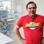 Helinando Pequeno de Oliveira veste camiseta vermelha com a estampa Bazinga! e posa em uma colagem com imagens de microscopia, estruturas microscópicas e elementos de um laboratório de pesquisa científica.