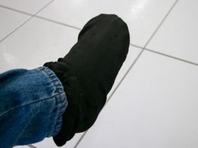 Pé coberto por meia preta, com parte da perna coberta por calça jeans.
