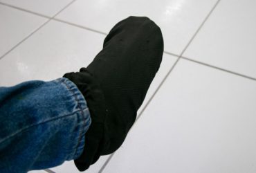 Pé coberto por meia preta, com parte da perna coberta por calça jeans.