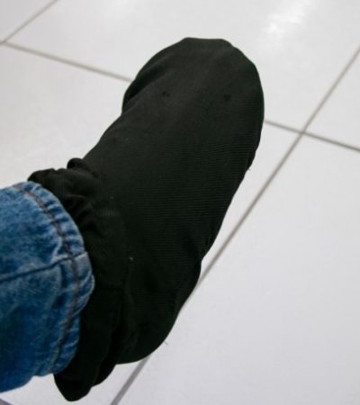 Pé coberto por meia preta, com parte da perna coberta por calça jeans.
